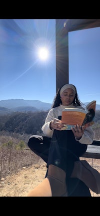 a woman sitting on a bench reading a book